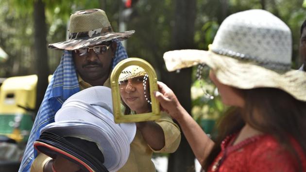 A man sells hats and caps to tourists ion a hot afternoon at Rajghat. (Sushil Kumar/HT PHOTO)