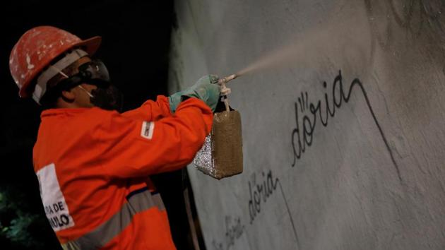 A municipal worker removes the writing ‘doria’ in reference to Sao Paulo's mayor Joao Doria, tagged by a Brazilian artist, known as Iaco, on Avenida 23 de Maio. (Nacho Doce / REUTERS)