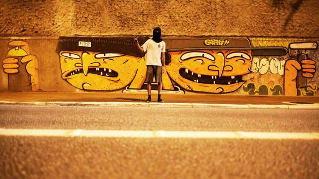 A ‘pichador’, a graffiti artist who tags buildings and landmarks with angular, runic fonts, poses for a photograph in front of a mural of a Brazilian artist ‘Humanos’, on a street in Sao Paulo, Brazil, April 11, 2017. The two faces on the mural are in reference to a "pichador" (L) and a graffiti artist. (Nacho Doce / REUTERS)