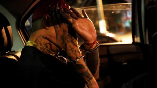 A Brazilian artist, known as Iaco, sits inside the police car after he was detained for painting on a wall on Avenida 23 de Maio. (Nacho Doce / REUTERS)