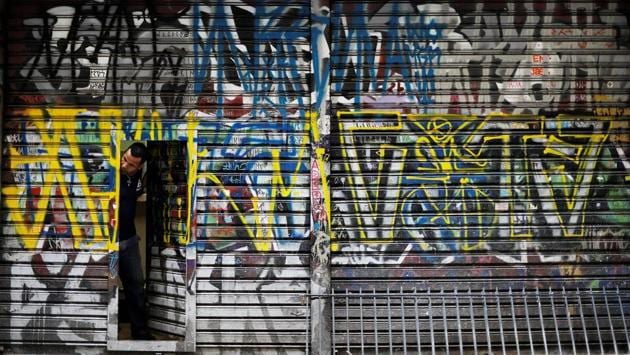 A man looks out of a door of his shop tagged by ‘pichadores’, graffiti . (Nacho Doce / REUTERS)