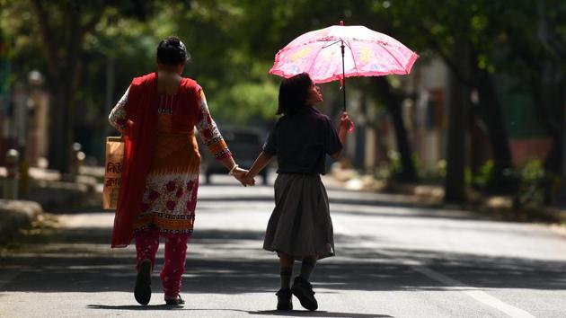 A girl covers herself with an umbrella against a harsh sun while returning from school. (Ravi Choudhary/HT PHOTO)