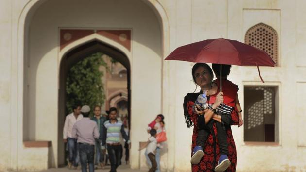 A mother holds her child under an umbrella to protect themselves from the scorching sun at Humayun's Tomb. Hot weather conditions continued to prevail in Delhi with maximum temperatures exceeding 40 degrees Celsius with intermittent showers and clouds. (Burhaan Kinu/HT PHOTO)