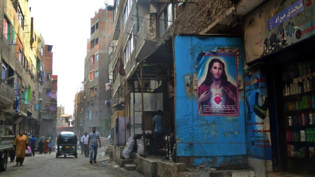 People walk past a poster bearing a portrait of Jesus Christ in the Zabalin area a day ahead of the visit of Pope Francis to the capital Cairo. (MOHAMED EL-SHAHED/AFP)