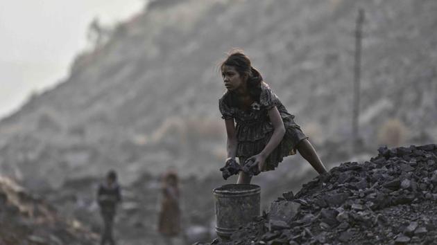 Rani (Name changed) keeps an eye on a mine checkpost, while collecting coal pieces illegally from an open-cast mine. (Ravi Choudhary/HT PHOTO)