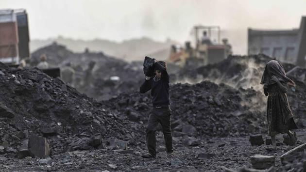 A young boy makes off with a chunk of coal from a mound of ore waiting to be loaded onto a truck. (Ravi Choudhary/HT PHOTO)