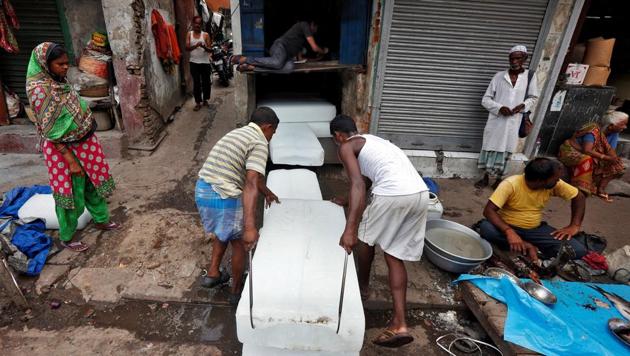 Workers stack blocks of ice on a hot summer day in Kolkata. (Reuters)