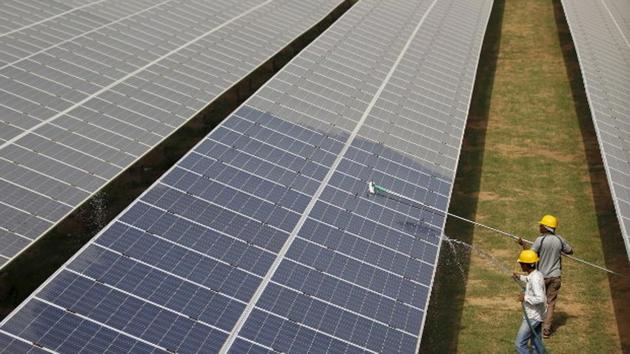 Workers clean photovoltaic panels inside a solar power plant in Gujarat. (File Photo) Workers clean photovoltaic panels inside a solar power plant in Gujarat. (File Photo)