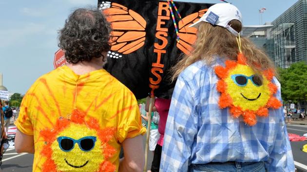 Men with cartoon suns wearing sunglasses on their backs stand with a "RESIST" sign as they await the start of a march by demonstrators down Pennsylvania Avenue. (Mike Theiler/REUTERS)