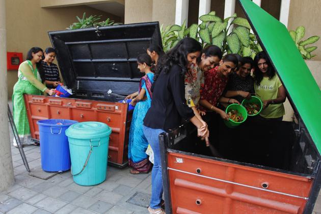 Residents of Marathon Onyx, Mulud, feed the two bio-bins with organic waste for producing compost.(Praful Gangurde/HT)