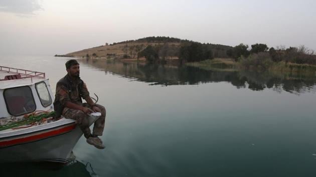 A member of the US-backed Syrian Democratic Forces (SDF) sits on a boat at the Lake Assad. Their direct land route from the territory they hold in the north is blocked by the Tabqa dam, which remains under IS control. So instead, they are running supplies across Lake Assad, an enormous reservoir created by the dam, as well as ferrying civilians fleeing Tabqa back across to safety. (Delil Souleiman/AFP) A member of the US-backed Syrian Democratic Forces (SDF) sits on a boat at the Lake Assad. Their direct land route from the territory they hold in the north is blocked by the Tabqa dam, which remains under IS control. So instead, they are running supplies across Lake Assad, an enormous reservoir created by the dam, as well as ferrying civilians fleeing Tabqa back across to safety. (Delil Souleiman/AFP)