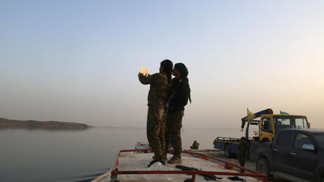 Female members of the US-backed Syrian Democratic Forces (SDF) take a piture as they stand on a boat at the Tabqa dam. On the water though, there is little sound except the engines of the boats and the thump of two US-led coalition helicopters overhead, helping secure the corridor. (Delil Souleiman/AFP) Female members of the US-backed Syrian Democratic Forces (SDF) take a piture as they stand on a boat at the Tabqa dam. On the water though, there is little sound except the engines of the boats and the thump of two US-led coalition helicopters overhead, helping secure the corridor. (Delil Souleiman/AFP)
