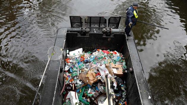 A worker cleans garbage with a boat in the canals of Amsterdam, on April 28, 2017, a day after Kings Day was celebrated. (Bas Czerwinski / AFP)