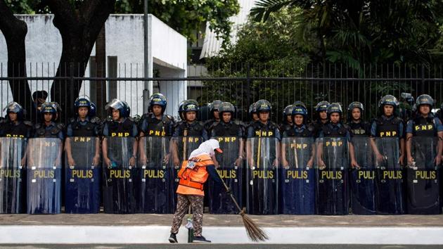A cleaner sweeps in front of police standing in formation near the venue of the Association of Southeast Asian Nations (ASEAN) summit off Manila Bay on April 26, 2017. Firebrand Philippine President Rodrigo Duterte is set to enjoy much-wanted foreign support for his deadly drug war when he hosts Southeast Asian leaders at the Manila summit this week, observers say. (Noel CELIS / AFP)