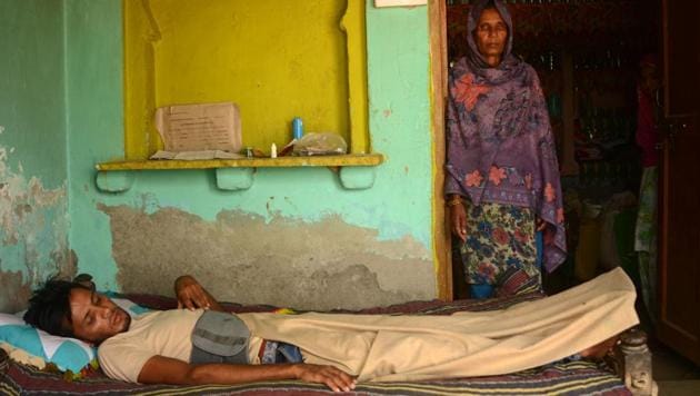 Azmat, who has suffered a spine injury, lying on a cot at his home in Jaisinghpur in Nur district of Haryana. His mother looks on.(HT PHOTO)