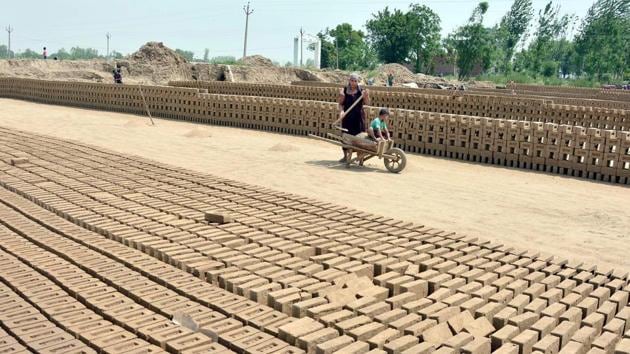 A labourer with her child at a brick-kiln at Bhullar village near Amritsar on Sunday. (Sameer Sehgal/HT Photo) A labourer with her child at a brick-kiln at Bhullar village near Amritsar on Sunday. (Sameer Sehgal/HT Photo)