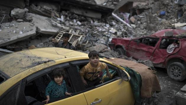 Children play inside a damaged car amid heavy destruction in a neighbourhood recently retaken by Iraqi security forces from Islamic State militants on the western side of Mosul.(AP)