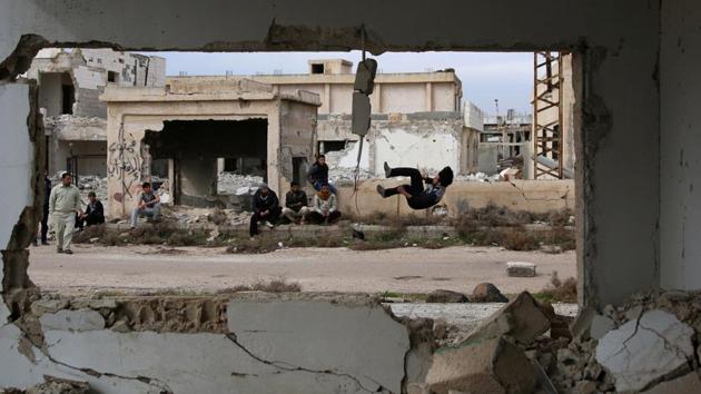 Kadiri and his friends somersault in the air, hold themselves up with just their arms and leap over piles of rubble. (Alaa Al-Faqir / Reuters) Kadiri and his friends somersault in the air, hold themselves up with just their arms and leap over piles of rubble. (Alaa Al-Faqir / Reuters)