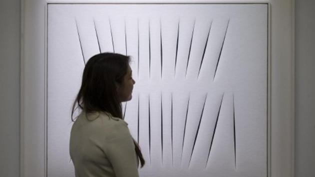 An employees of Sotherby's auction house studies "Concetto Spaziale, Attese", by Lucio Fontana during a press preview in London on January 28, 2015, ahead of the Impressionist & Modern Art Evening Sale on February 3, 2015. (AFP) An employees of Sotherby's auction house studies "Concetto Spaziale, Attese", by Lucio Fontana during a press preview in London on January 28, 2015, ahead of the Impressionist & Modern Art Evening Sale on February 3, 2015. (AFP)