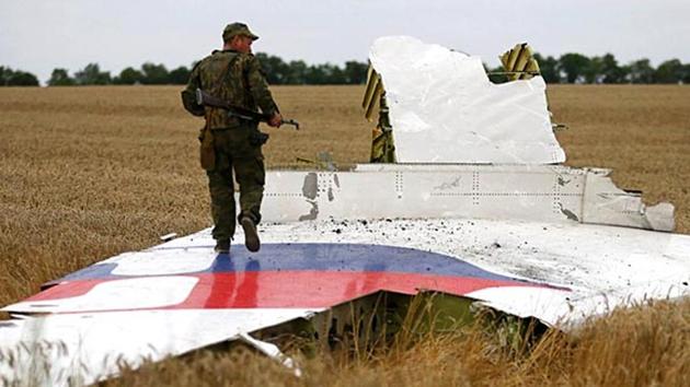 An armed pro-Russian separatist stands on part of the wreckage of the Malaysia Airlines Boeing 777 plane after it crashed near the settlement of Grabovo in the Donetsk region, in this July 17, 2014 file picture.(Reuters File Photo)