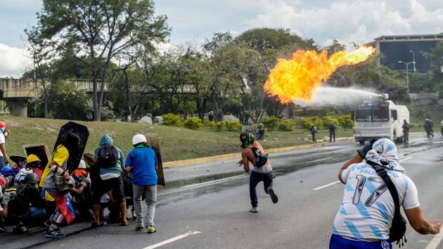 A Venezuelan opposition activist throws a molotov cocktail to a police water cannon truck during clashes within a march against President Nicolas Maduro. (FEDERICO PARRA / AFP)