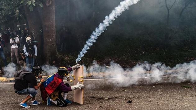 Venezuelan opposition activists protect themselves behind a makeshift shield, during clashes with police . (JUAN BARRETO / AFP)