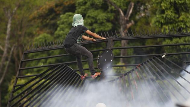 A demonstrator climbs on the fence of the La Carlota airport during an opposition May Day march in Caracas. (Ariana Cubillos / AP)