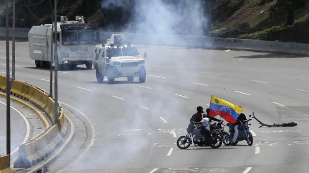 Bolivarian National Guard vehicles advance toward demonstrators on a highway. (Fernando Llano / AP)