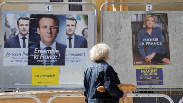 A woman walks past new official posters for the candidates in the 2017 French presidential election, Emmanuel Macron (L), head of the political movement En Marche !, or Onwards !, and Marine Le Pen (R) of French National Front (FN) political party, in Nice, France, May 2, 2017. REUTERS/Eric Gaillard/Files (Reuters) A woman walks past new official posters for the candidates in the 2017 French presidential election, Emmanuel Macron (L), head of the political movement En Marche !, or Onwards !, and Marine Le Pen (R) of French National Front (FN) political party, in Nice, France, May 2, 2017. REUTERS/Eric Gaillard/Files (Reuters)