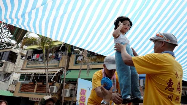 A girl standing above the crowd with the support of an elaborate rig of hidden metal rods. Buns from the top of the tower carry the most points and the highest scorer is the winner.  (Bobby Yip/REUTERS) 