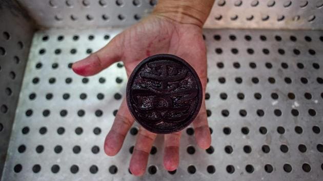 A traditional bun baker holds a stamp which reads (Peace Safe), used to mark buns made during the annual Cheung Chau bun festival in Hong Kong. (Anthony Wallace/AFP) 