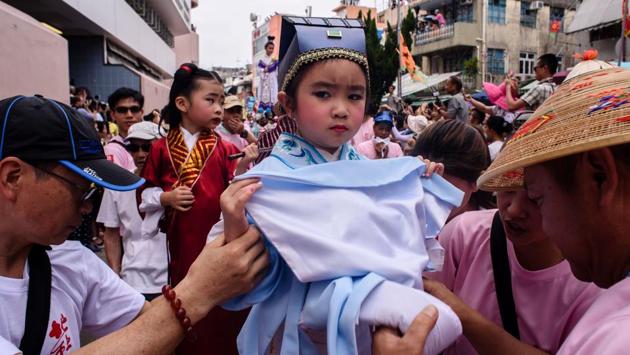 A young girl (C) dressed as a deity takes part in a parade. Young children in intricate outfits -- posing as deities, local sporting heroes and even politicians gave the impression of floating above the crowds as they were wheeled around on high pedestals. (Anthony Wallace/AFP) 
