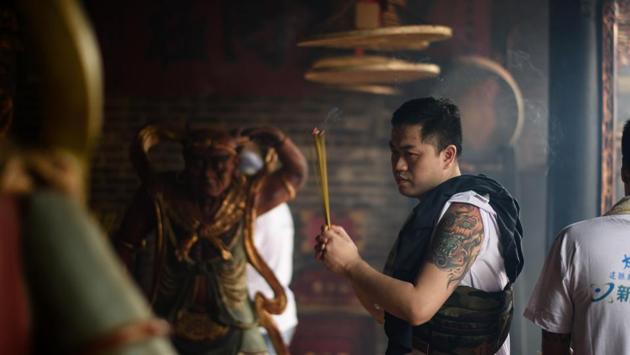 A devotee prays with joss sticks in a temple. A late-night scramble by agile competitors up an 18-metre (60-foot) tower made from imitation buns was scheduled to top off the festivities. (Anthony Wallace/AFP) 