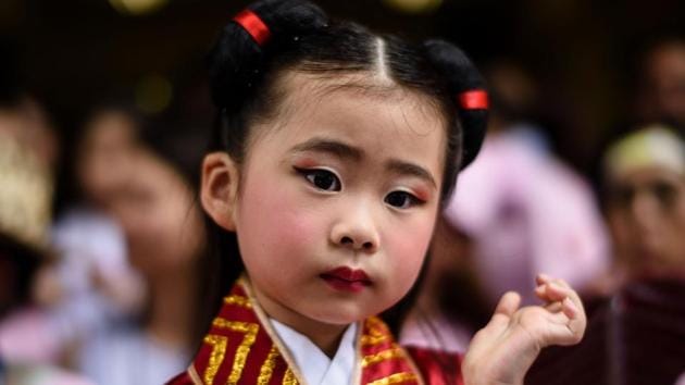 A young girl dressed as a deity prepares to take part in a parade. (Anthony Wallace/AFP) 