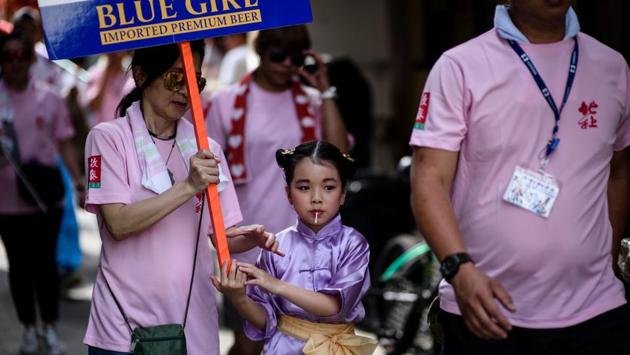 A young girl (C) dressed as a deity enjoys a lollipop after taking part in a parade. (Anthony Wallace/AFP) 