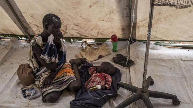 A mother sits by her child suffering from cholera in a tent converted into a temporary field hospital near the remote village of Dor in the Awerial. (AFP)