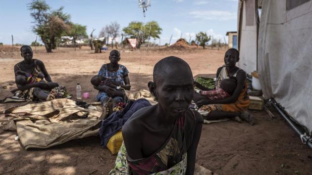 A cholera-stricken woman showing signs of malnutrition sits next to fellow patients (background) outside a temporary field hospital. (AFP)