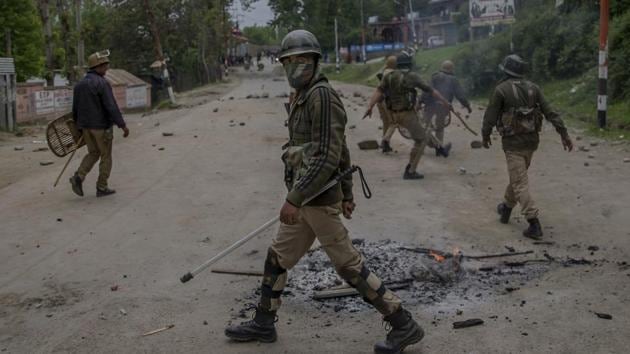 A policeman keeps vigil while his others clear the road of rocks and stones thrown by protesters in Budgam, about 20 kms southwest of Srinagar, on May 3, 2017.(AP File Photo)