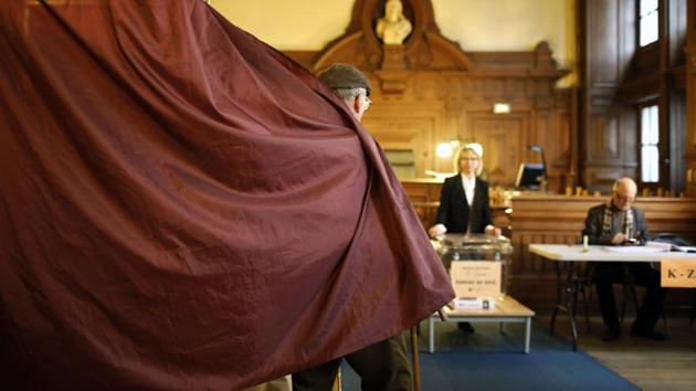 A man exits a voting booth after casting his ballot as part of the second round of the French presidential election in Paris. Voters across France are choosing a new president in an unusually tense and important election that could decide Europe's future, making a stark choice between pro-business progressive Emmanuel Macron and far-right populist Marine Le Pen. (Laurent Cipriani/AP)