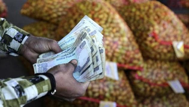 A trader counts rupees at wholesale vegetables market on the outskirts of Jammu on March 6.(AP Photo)