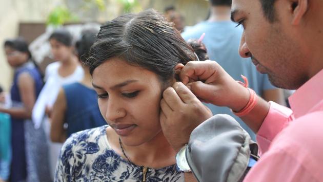 A man helps his wife take off her earrings outside an exam centre in Bhopal. The Central Board of Secondary Education (CBSE), which conducts the test, issued a slew of instructions for the candidates, including restriction on use of toilet in the last 30 minutes of the exam. (Mujeeb Faruqui/HT Photo) A man helps his wife take off her earrings outside an exam centre in Bhopal. The Central Board of Secondary Education (CBSE), which conducts the test, issued a slew of instructions for the candidates, including restriction on use of toilet in the last 30 minutes of the exam. (Mujeeb Faruqui/HT Photo)