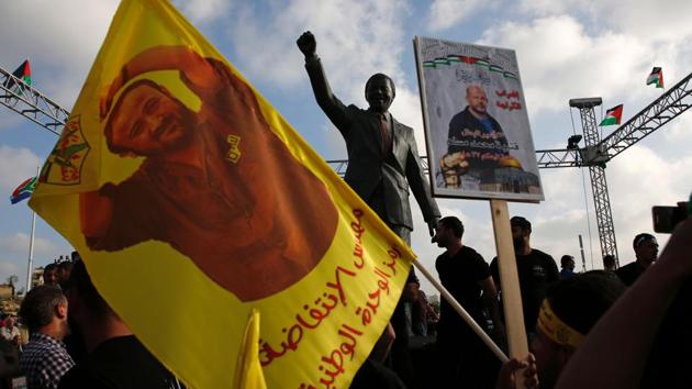 Protesters hold up portraits of Palestinian leader and prominent prisoner Marwan Barghouti in front of a statue of Nelson Mandela in the West Bank city of Ramallah during a demonstration in support of Palestinian prisoners on hunger strike in Israeli jails. (Abbas Momani/AFP)