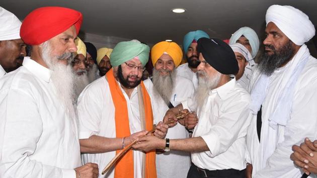 Punjab chief minister Captain Amarinder Singh being honoured by SGPC chief secretary Harcharan Singh (2R) at Golden Temple, Amritsar on Monday. (Sameer Sehgal/HT Photo)
