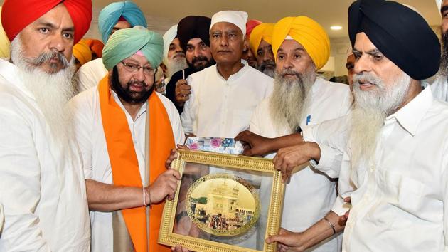 Punjab chief minister Captain Amarinder Singh being honoured by SGPC chief secretary Harcharan Singh (2R) at Golden Temple, Amritsar on Monday. (Sameer Sehgal/HT Photo)