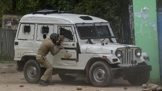 Representative Image: A policeman takes cover behind an armoured vehicle from rocks thrown at him by Kashmiri students during a protest in Budgam, about 20 kilometers southwest of Srinagar. (AP Photo) Representative Image: A policeman takes cover behind an armoured vehicle from rocks thrown at him by Kashmiri students during a protest in Budgam, about 20 kilometers southwest of Srinagar. (AP Photo)