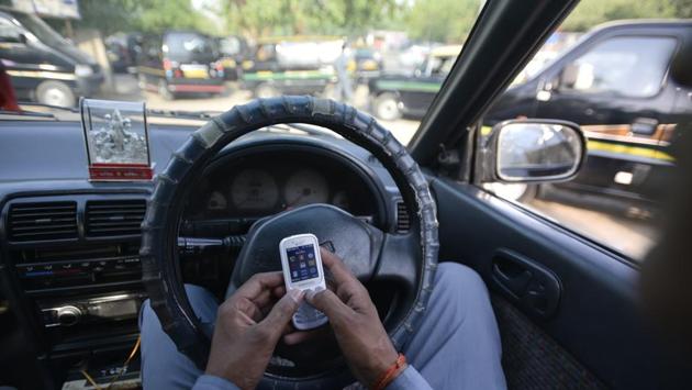 Sitting in his car at the parking lot waiting for passengers, Kapri spends his time checking messages or watching TV with his mates. (Ravi Choudhary/HT PHOTO)