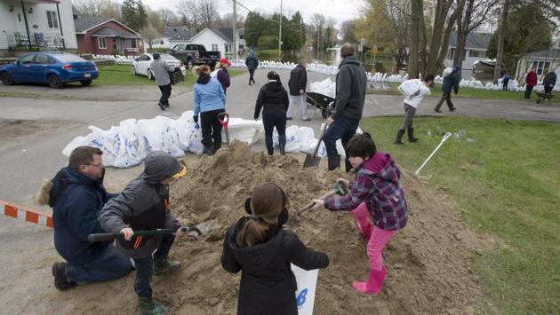 People fill sandbags to try to fend off the floodwaters in Deux-Montagnes. Heavy rains and melting snowpack across Quebec have so far flooded thousands of residences in the province, forcing the evacuation of people in almost 150 municipalities. (Ryan Remiorz/The Canadian Press/AP)