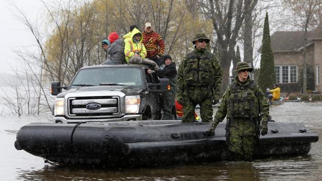Canadian soldiers wait with their boat while checking on residents in a flooded residential area in Gatineau. The ground is saturated and unable to absorb any more water. (Chris Wattie/REUTERS)