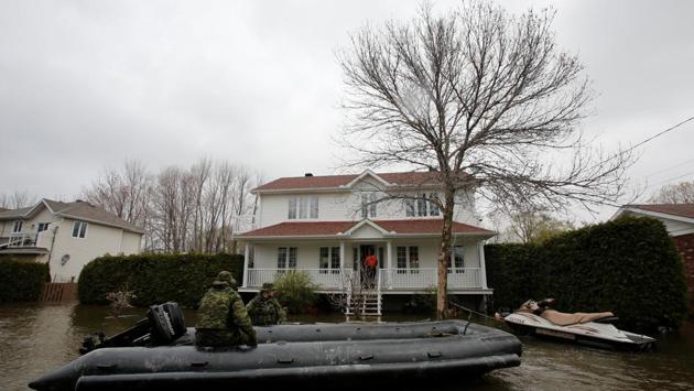 Canadian soldiers wait in their boat as a city official checks on residents. The flooding took her and most others here by surprise, and she barely had time to erect a small sandbag wall around her property. (Chris Wattie/REUTERS)