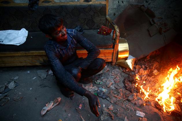Khodor, 20, reacts to burning plastic inside a workshop where he works. (Bassam Khabieh / Reuters) Khodor, 20, reacts to burning plastic inside a workshop where he works. (Bassam Khabieh / Reuters)